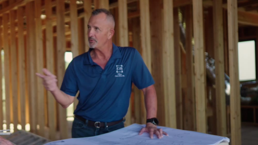 Two builders reviewing plans inside a house still in framing