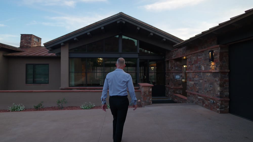A finished custom home at dusk, seen across the motor court